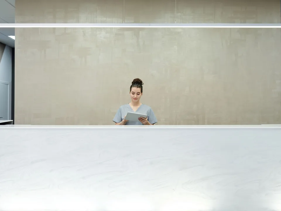 Receptionist assisting visitors with a tablet at a modern office front desk