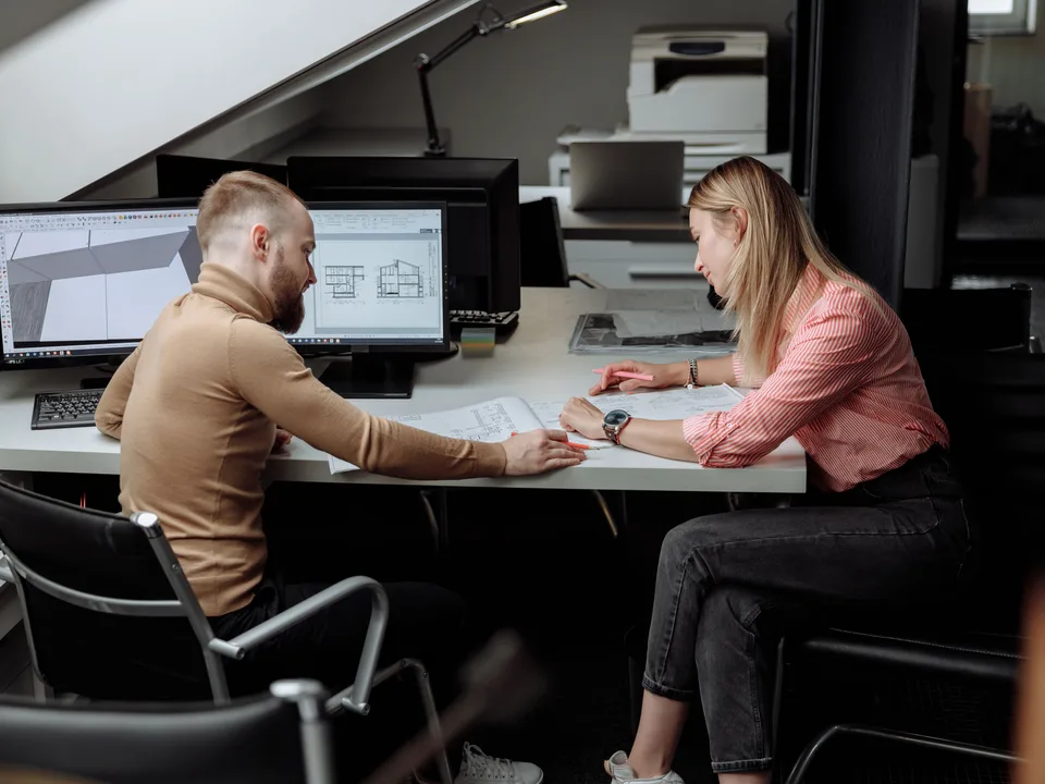 Dos arquitectos revisando planos de construcción y diseño en una oficina de una constructora