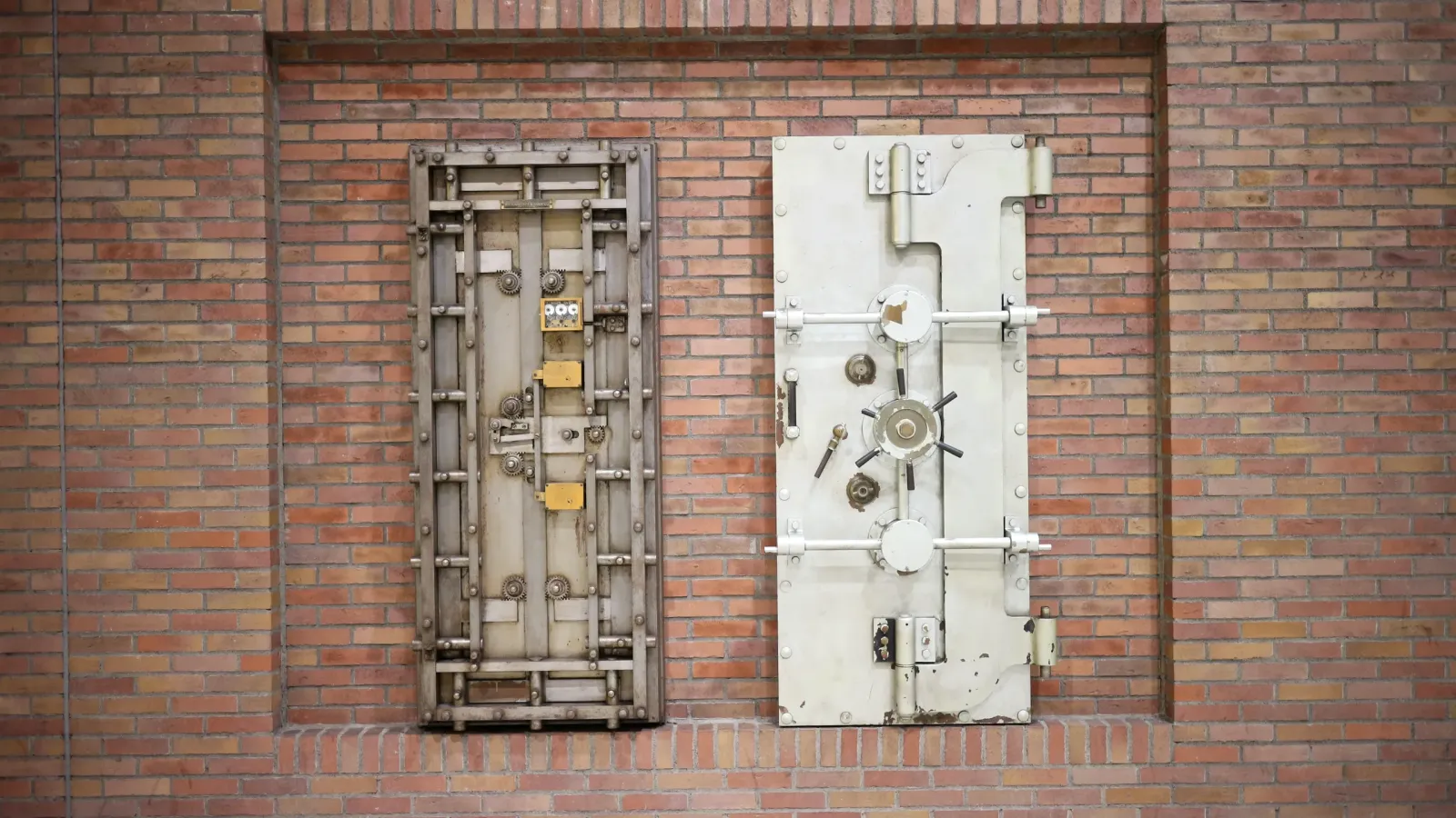 Dos puertas de acero de bóveda de seguridad, con cerrojos y manivelas, empotradas en una pared de ladrillo