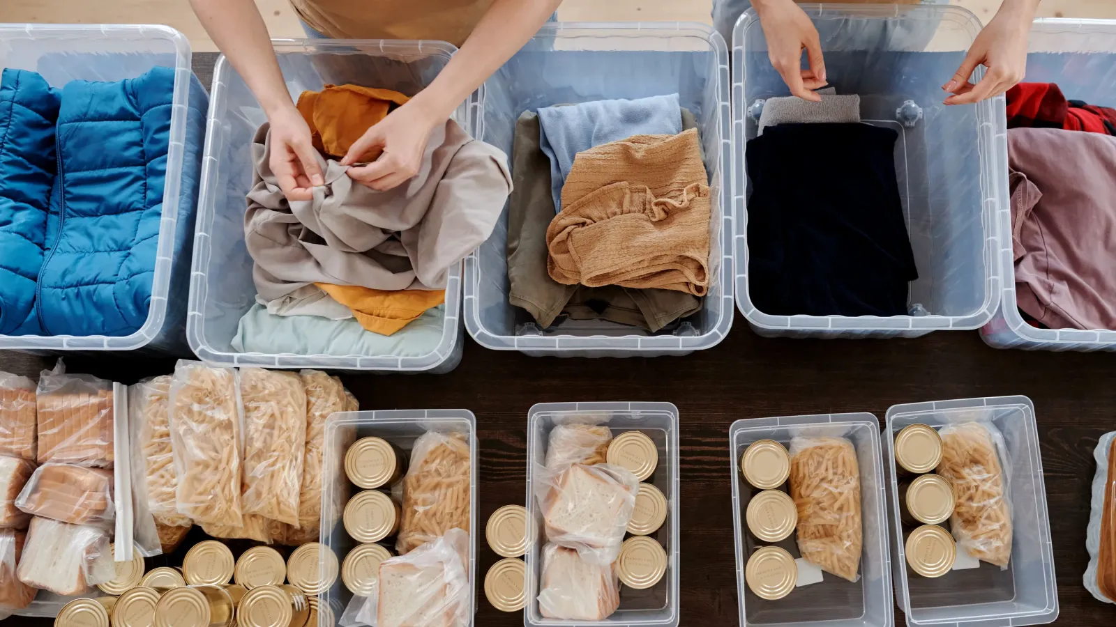 Volunteers sort donated clothes and food into clear bins, seen from above