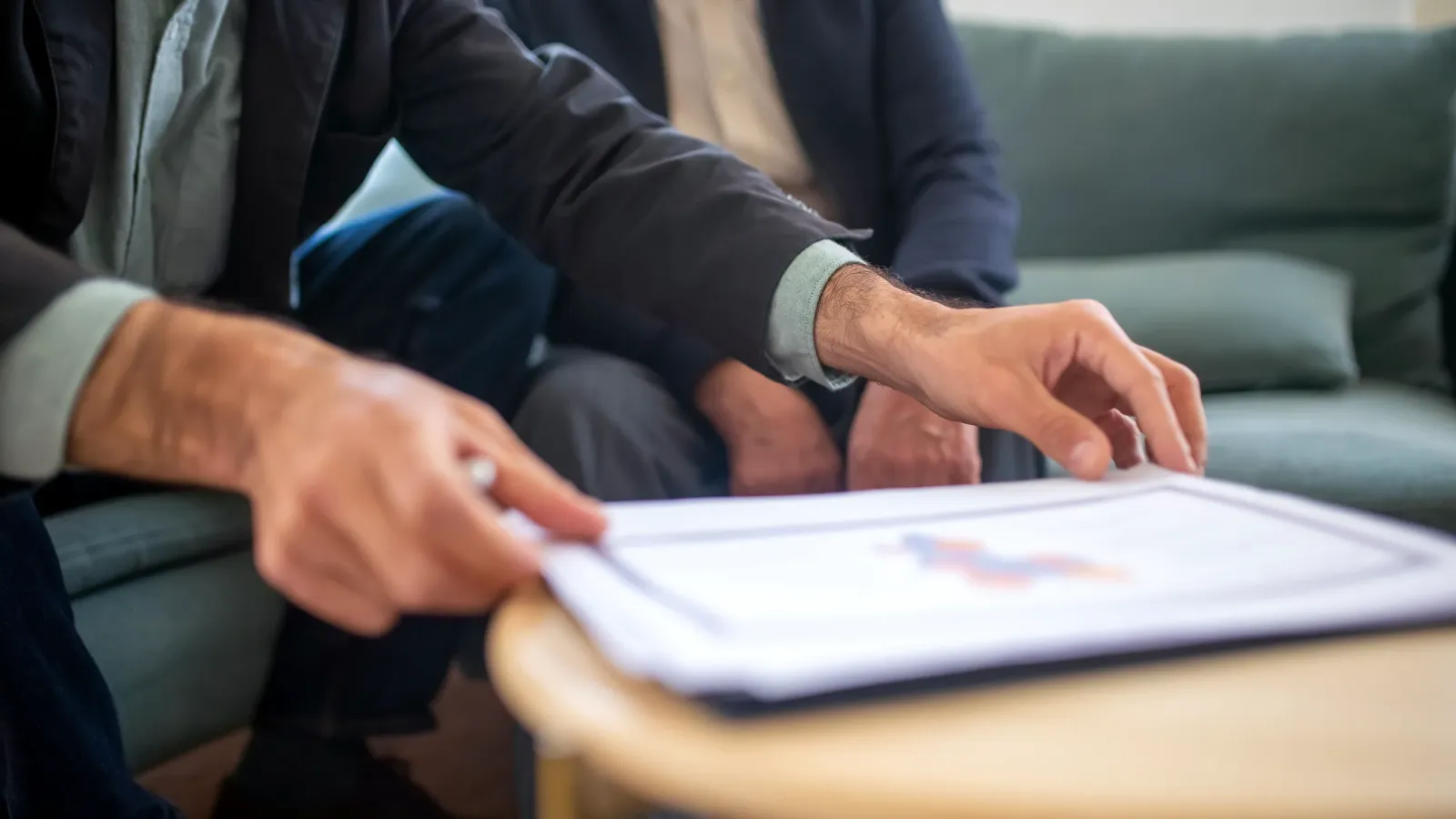 Asesor señala un informe con gráficos sobre una mesa durante una reunión con un cliente