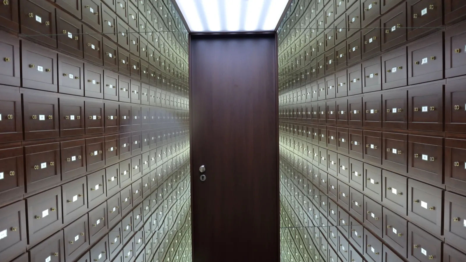 Bóveda con paredes de cajas de seguridad numeradas y una puerta de madera al fondo