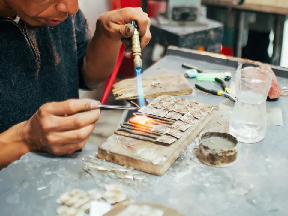Silversmith soldering silver pieces in his workshop in Cusco