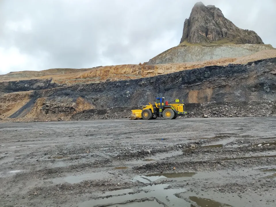 Cargador frontal amarillo en una mina a tajo abierto de los Andes, con un pico rocoso al fondo